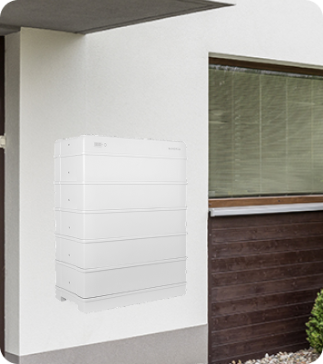A modern white home battery storage unit installed on the exterior wall of a house