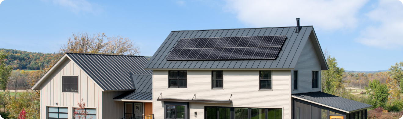 A contemporary house featuring a gray metal roof with a large array of solar panels