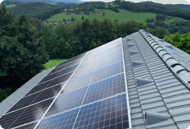 Solar panels on a rooftop with a green landscape