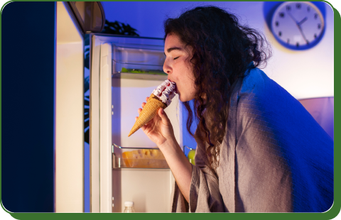 A person is comfortably getting food from a lit refrigerator at night demonstrating the benefit of having reliable power during a blackout